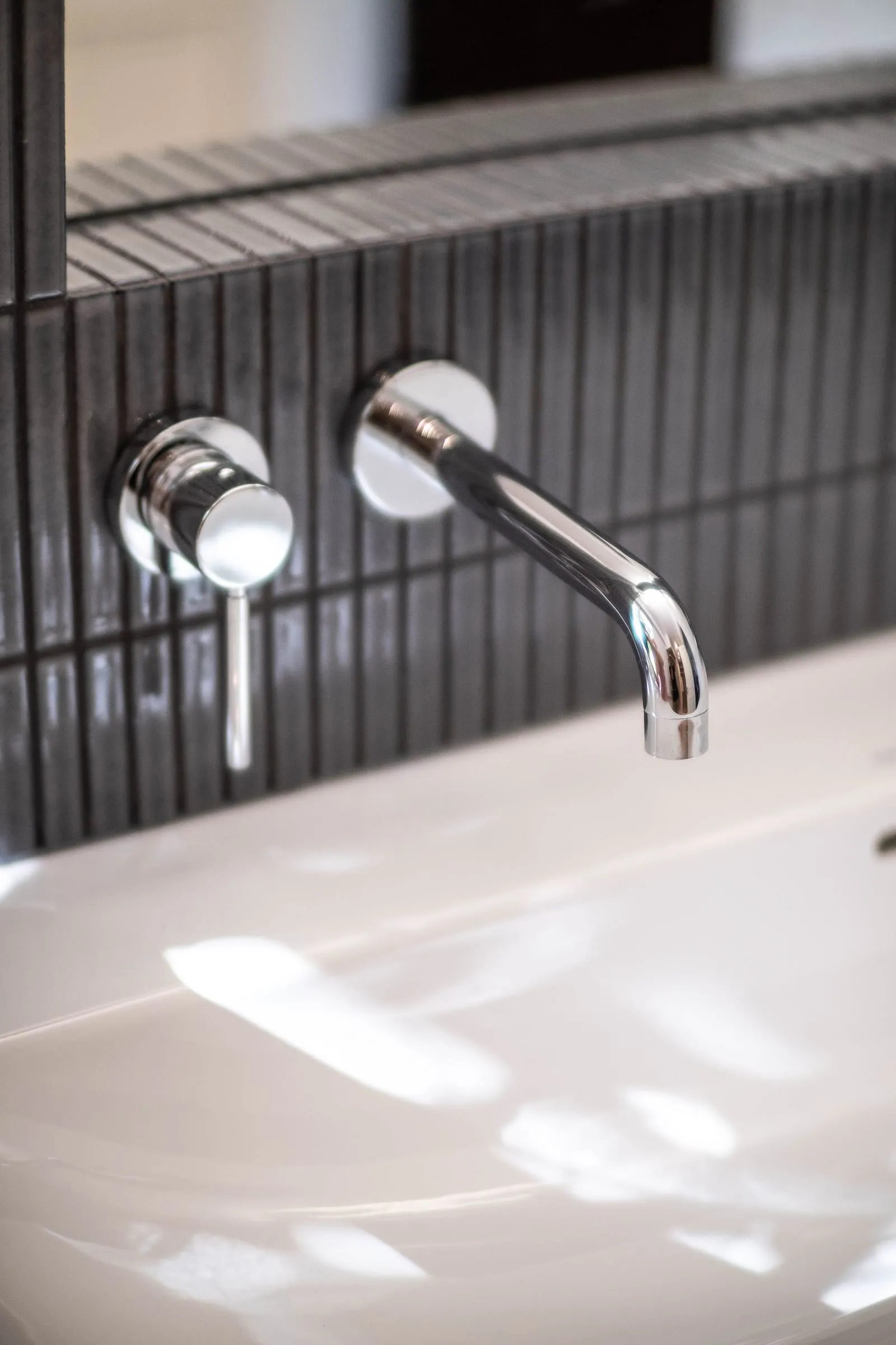 Robinetterie murale chromée sur carrelage strié noir, salle de bain D1