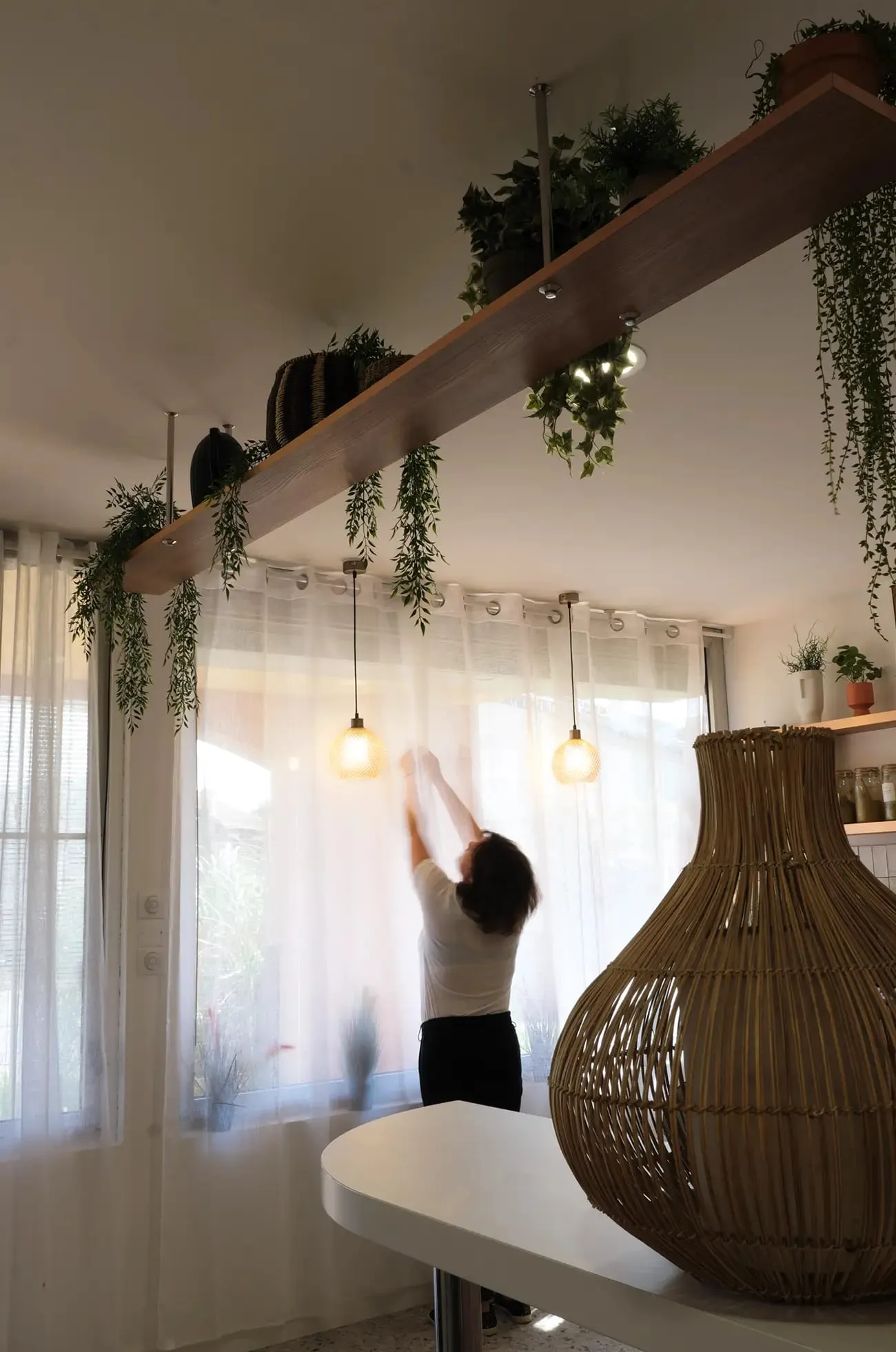 Étagère suspendue en bois avec plantes au-dessus de la table, salon Pourquoi Ailleurs, Blagnac