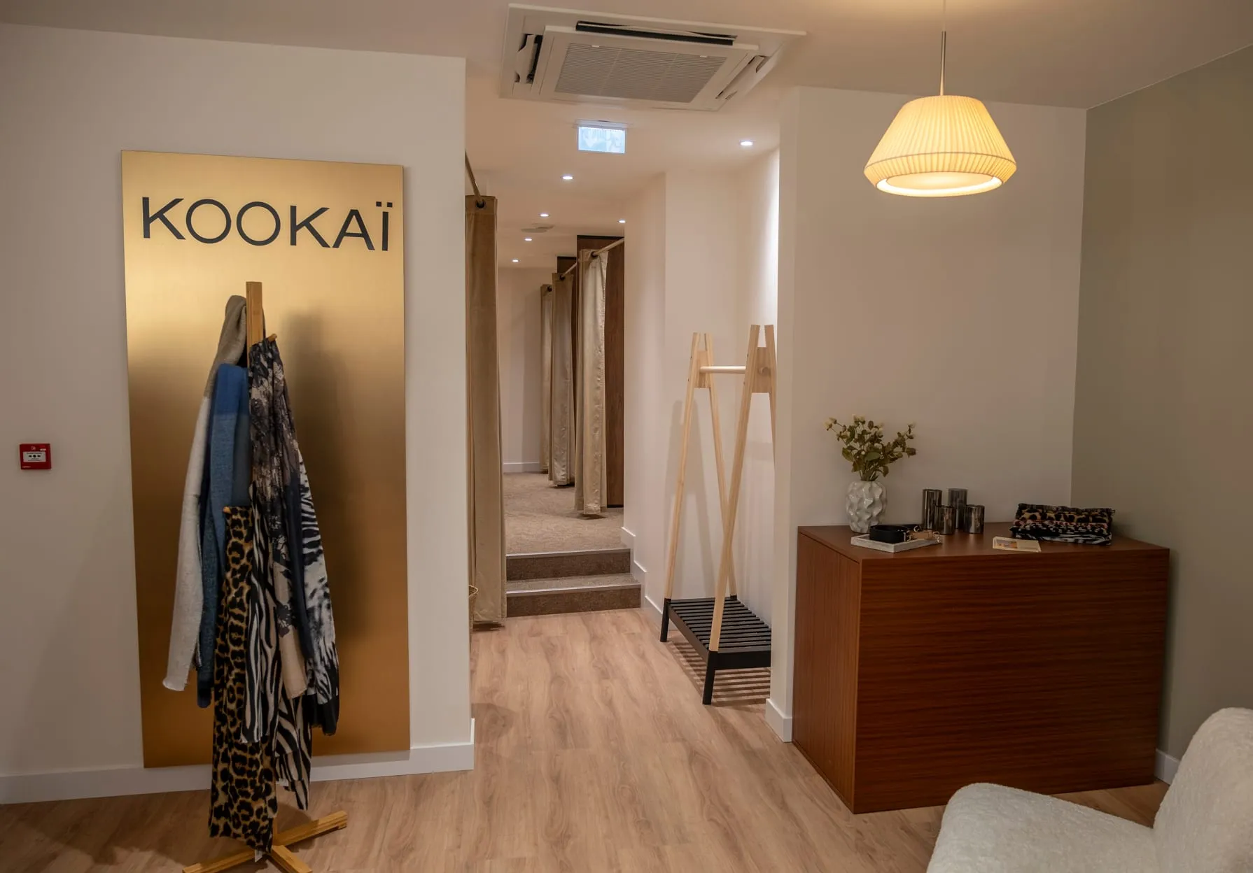 Panneau doré Kookaï à l'entrée des cabines, portant en bois et console en noyer