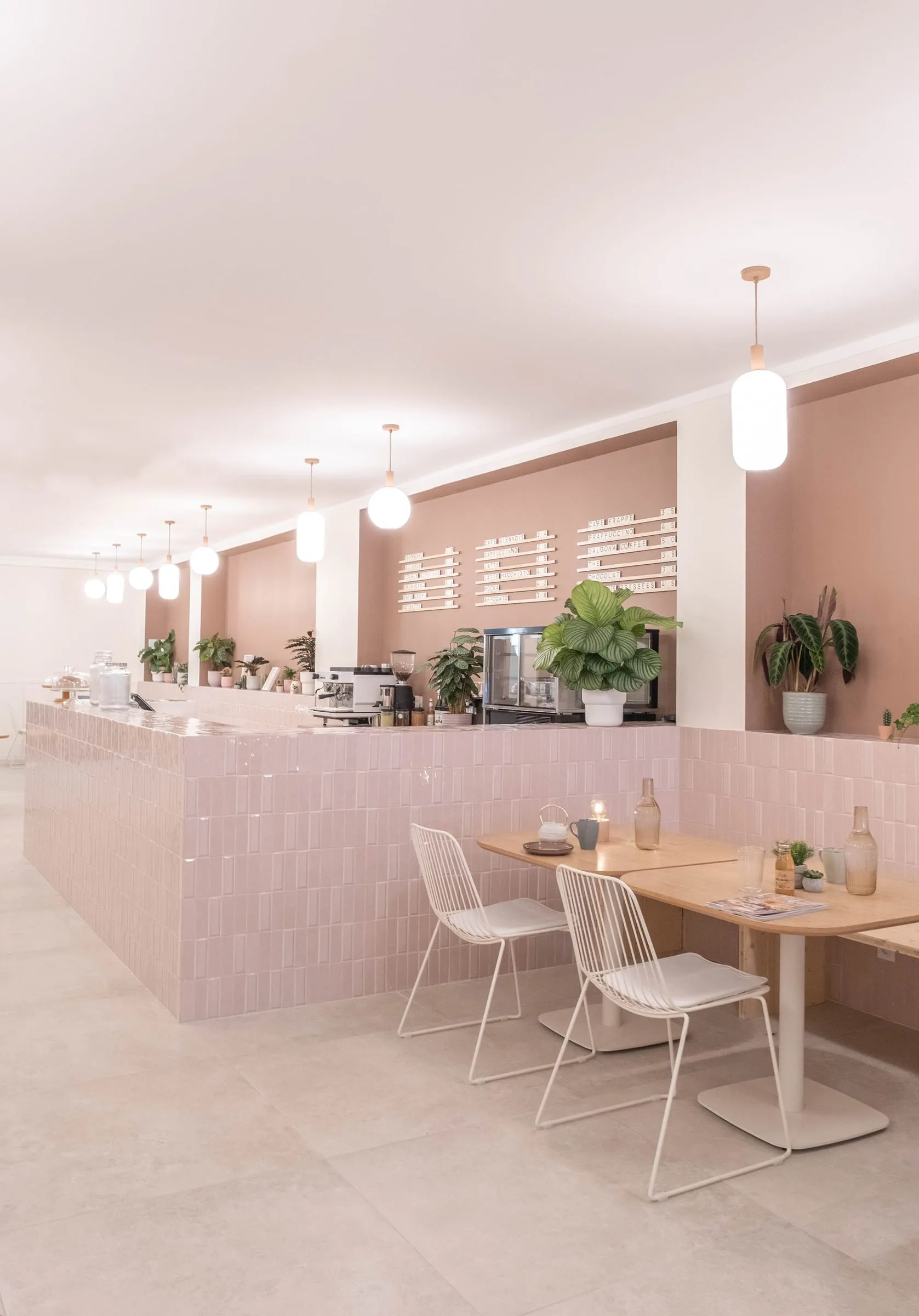 Salle du Kimi Coffee, comptoir en zellige rose, tables en bois et chaises blanches