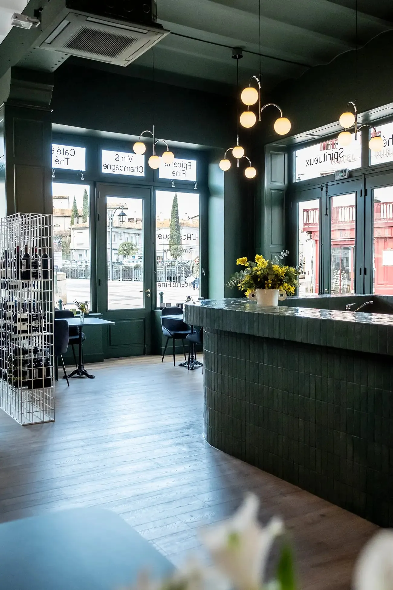 Intérieur de L'Atypique vers la vitrine, comptoir vert et suspensions globe