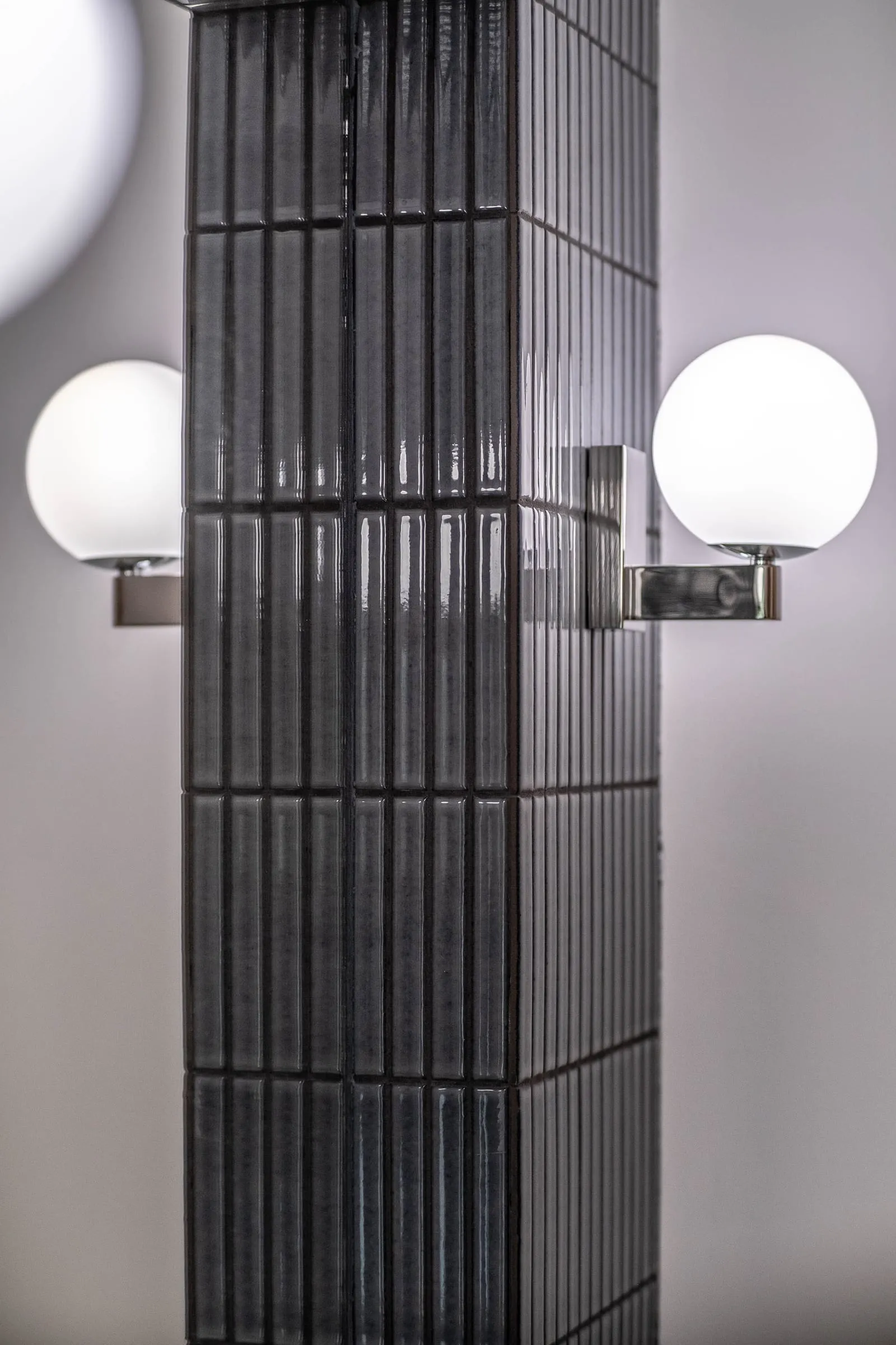 Deux appliques globe encadrant le miroir sur carrelage strié noir, D1