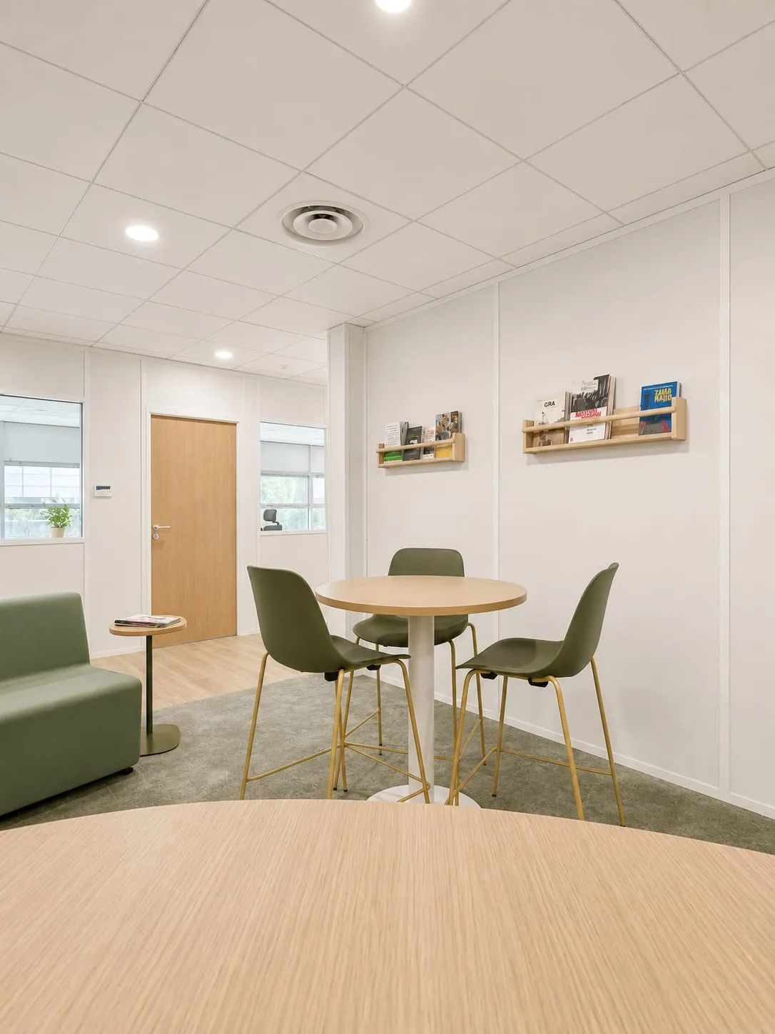 Espace de pause, banquette verte et table ronde en bois, CMCAS