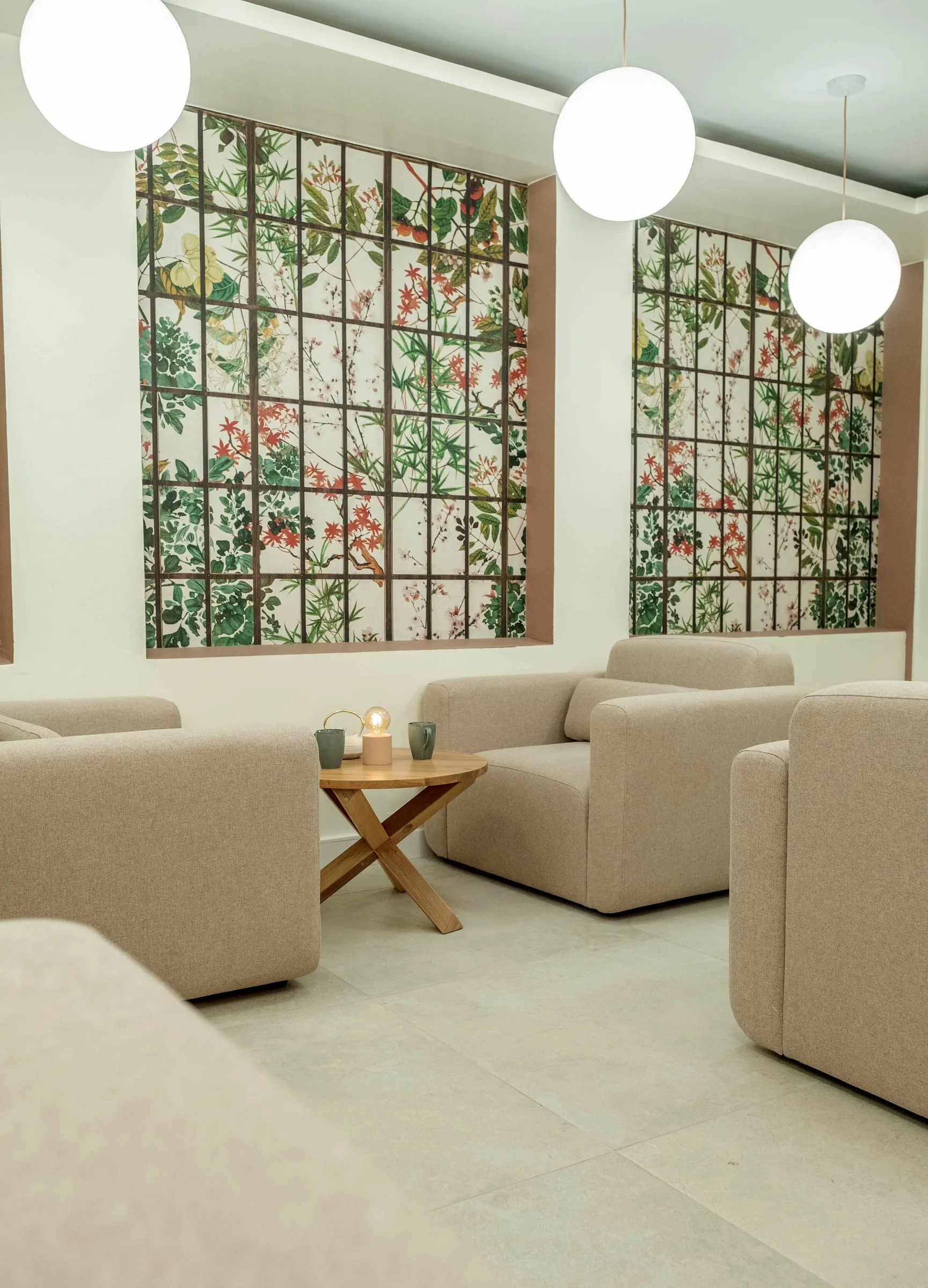 Coin salon aux fauteuils crème, papier peint fleuri et suspensions globe, Kimi Coffee