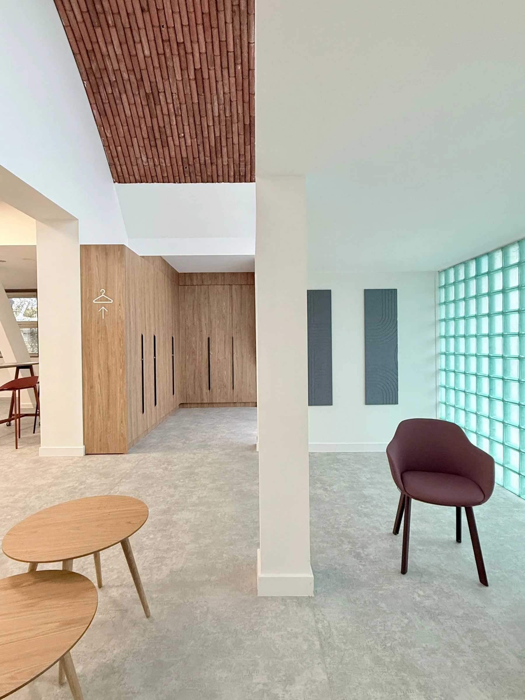 Fauteuil bordeaux, tables basses et pavés de verre sous la voûte, ATR
