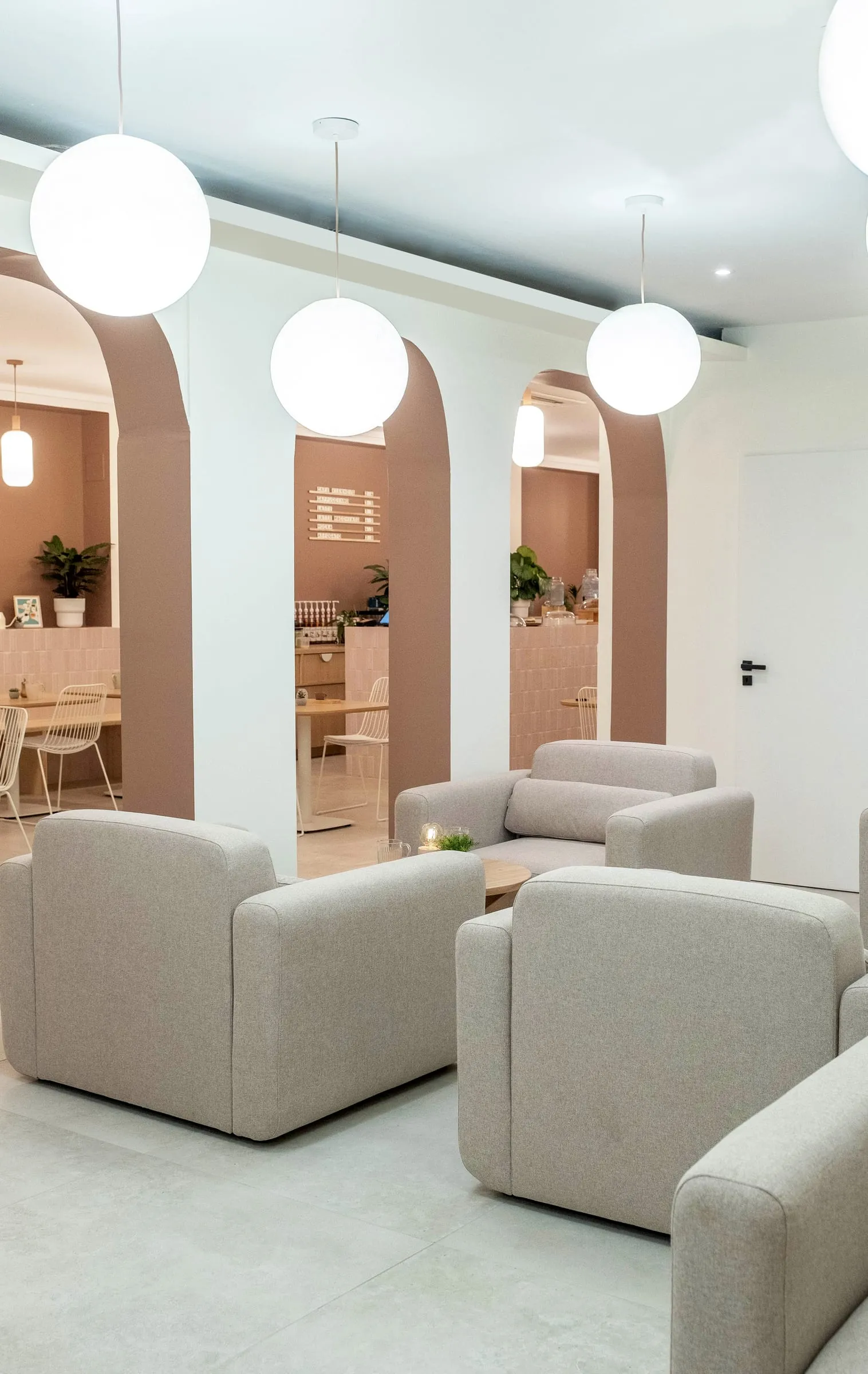 Arches et fauteuils crème sous des suspensions globe, Kimi Coffee, Castres