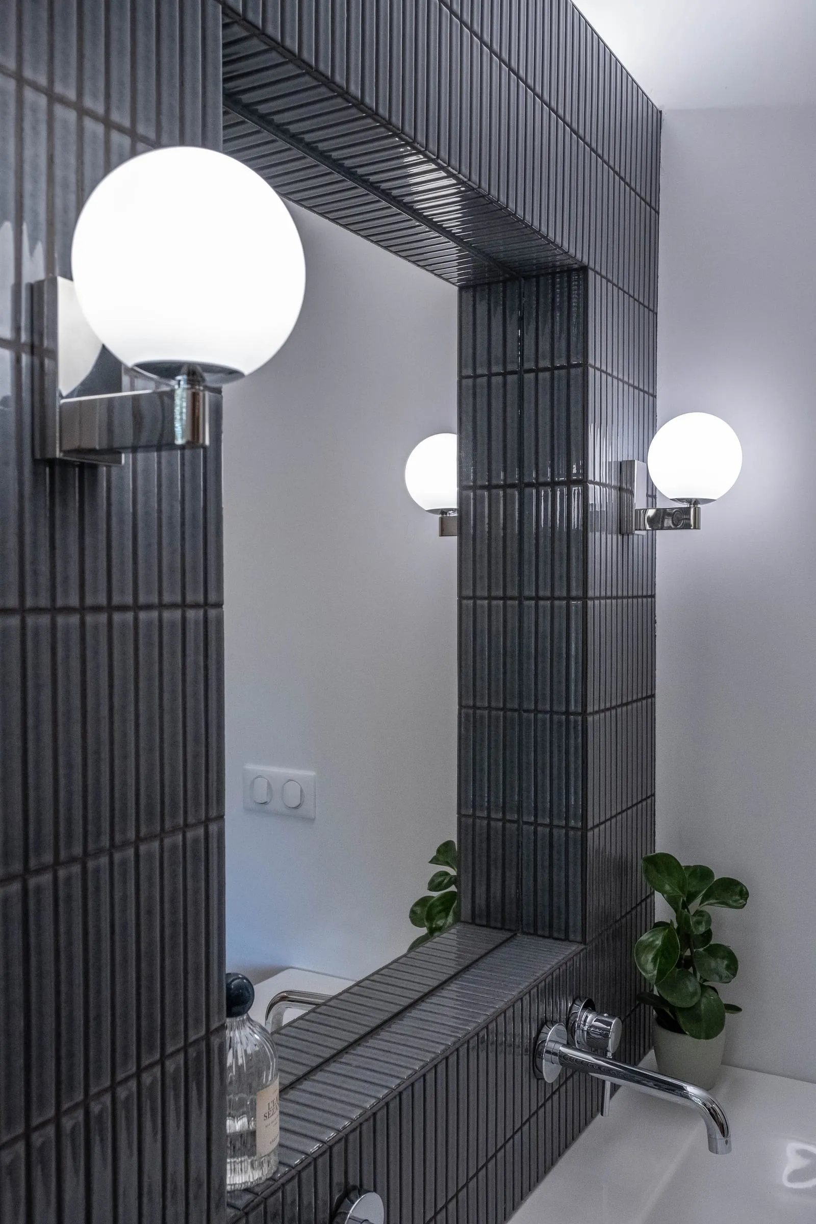 Miroir et appliques globe sur le mur en carrelage strié noir, D1