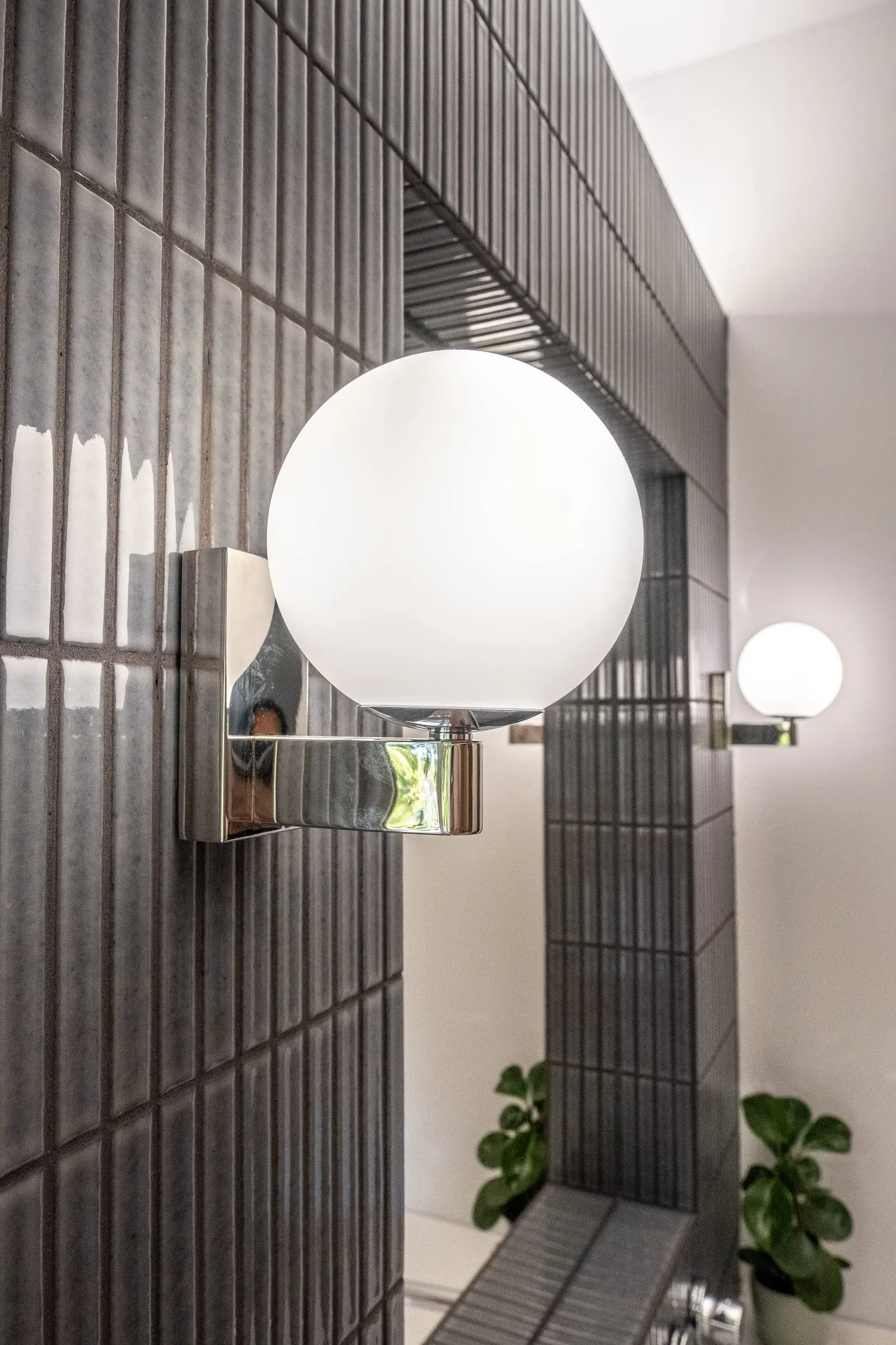 Applique globe chromée devant le carrelage strié noir, D1