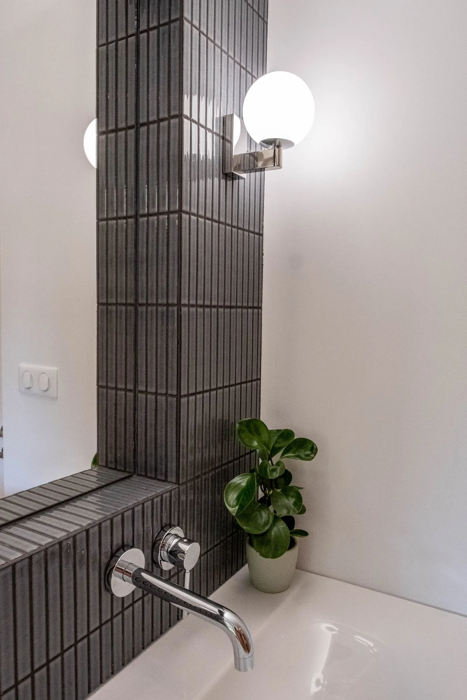 Angle de la baignoire en carrelage noir, applique et plante, D1