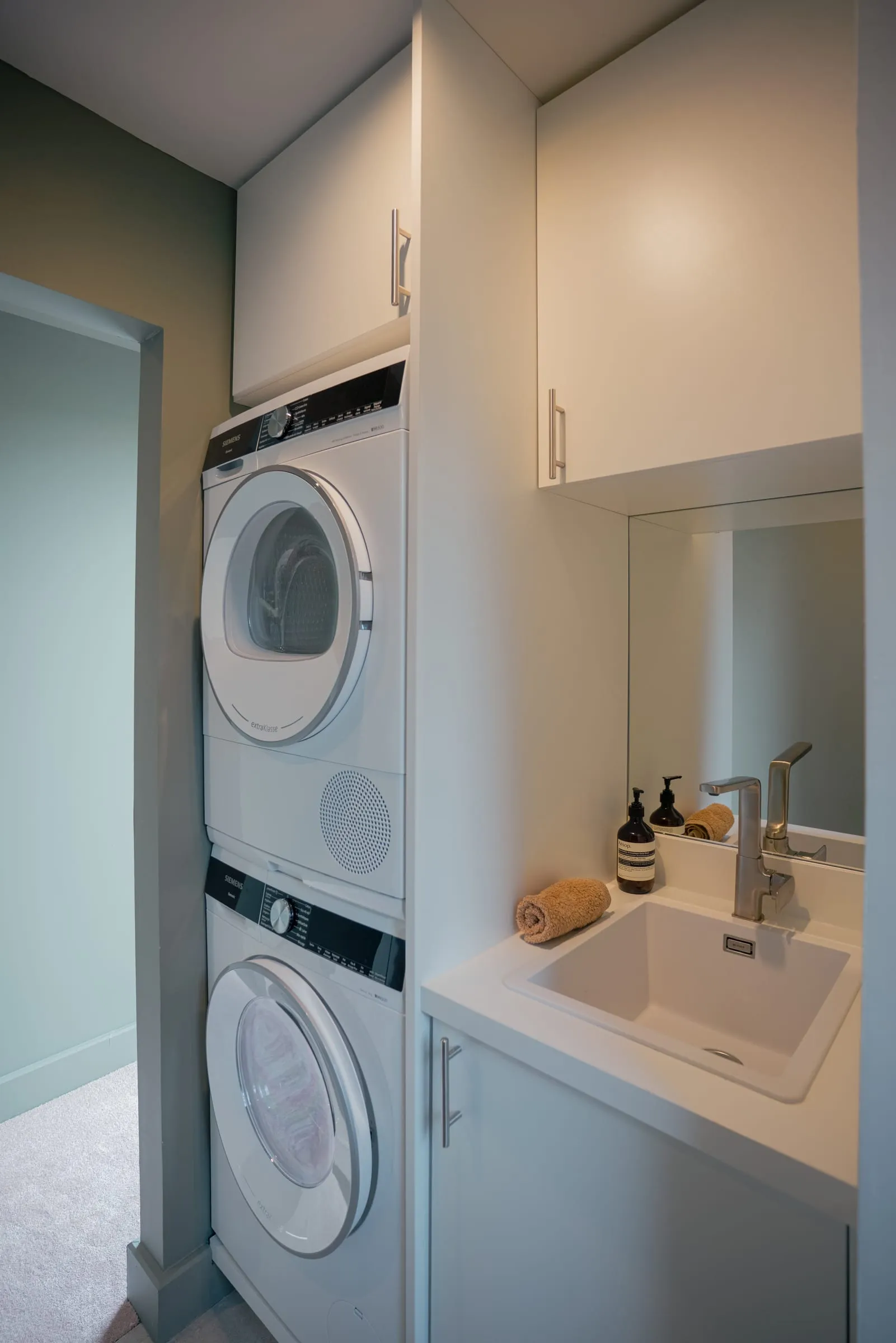 Buanderie vert sauge avec lave-linge superposé et plan de travail, Maison V1